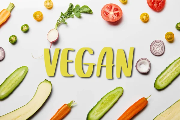 Draufsicht auf frisches geschnittenes Gemüse auf weißem Hintergrund mit veganer Illustration — Stockfoto