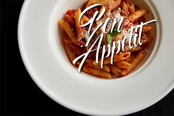 Top view of tasty bolognese pasta with tomato sauce and Parmesan in white plate isolated on black, bon appetit illustration — Stock Photo