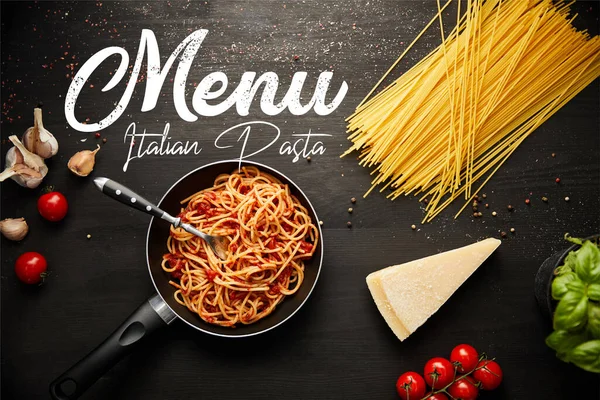 Top view of tasty bolognese pasta in frying pan on black background with fresh ingredients, italian pasta menu illustration — Stock Photo