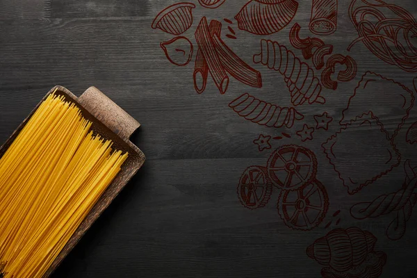 Vista dall'alto di spaghetti crudi su fondo di legno nero, illustrazione alimentare — Foto stock