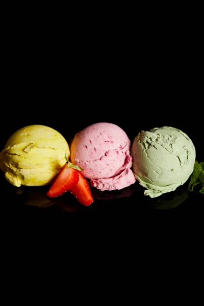 Délicieuses boules de crème glacée citron, fraise et menthe isolées sur noir — Photo de stock