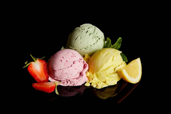 Delicious lemon, strawberry and mint ice cream balls isolated on black — Stock Photo