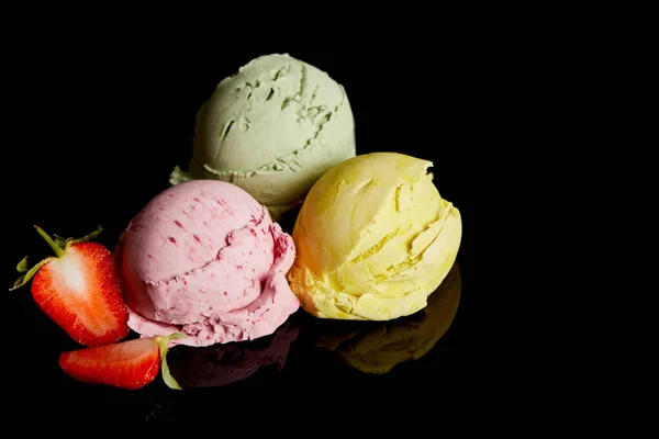 Deliciosas bolas de helado de limón, fresa y menta aisladas en negro - foto de stock