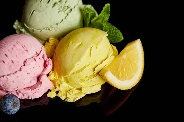 Delicious lemon, berry and mint ice cream balls isolated on black — Stock Photo