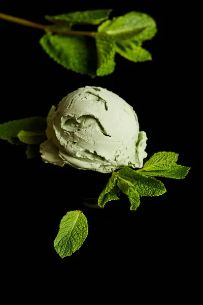 Fresh delicious green mint ice cream with leaves isolated on black — Stock Photo