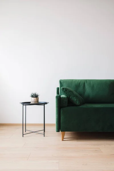 Зеленый диван с подушкой и журнальным столиком — стоковое фото