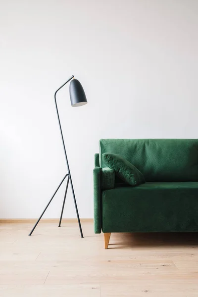 Green sofa with pillow near metal modern floor lamp — Stock Photo