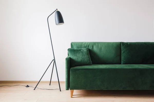 Canapé vert avec oreiller près du lampadaire moderne en métal — Photo de stock