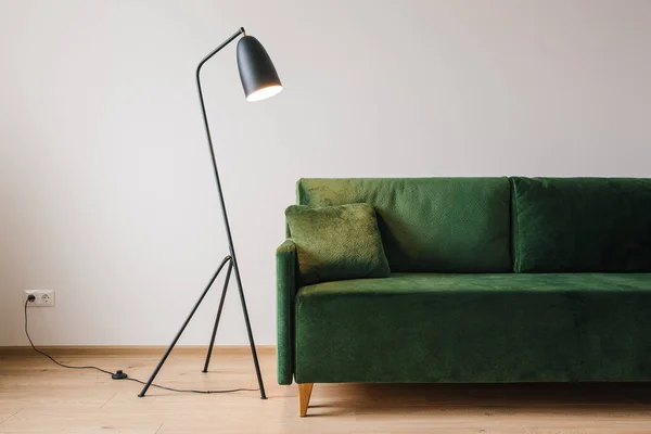 Green sofa with pillow near metal modern floor lamp — Stock Photo