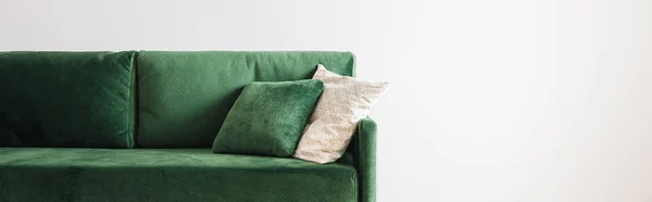 Moderno sofá verde con almohadas en amplia habitación cerca de la pared gris, tiro panorámico - foto de stock