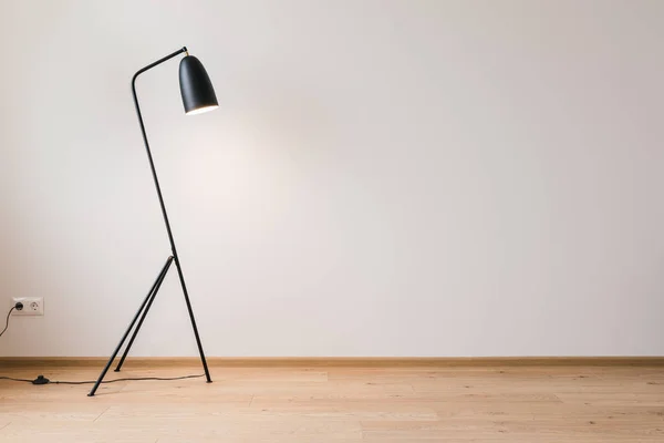 Металлическая современная напольная лампа возле серой стены — стоковое фото