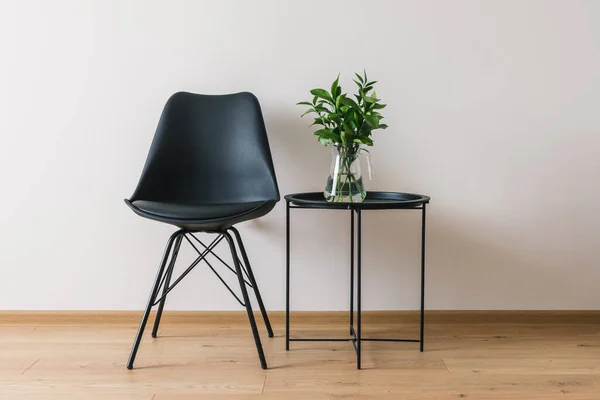 Mesa de café preto com planta verde perto da cadeira moderna — Fotografia de Stock