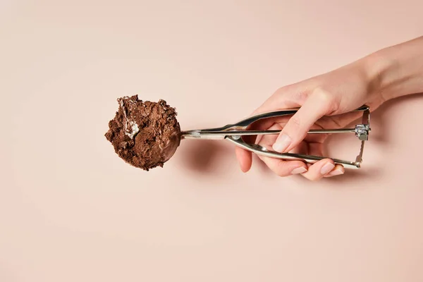 Vista recortada de la mujer sosteniendo cucharada con bola de helado de chocolate sobre fondo rosa - foto de stock