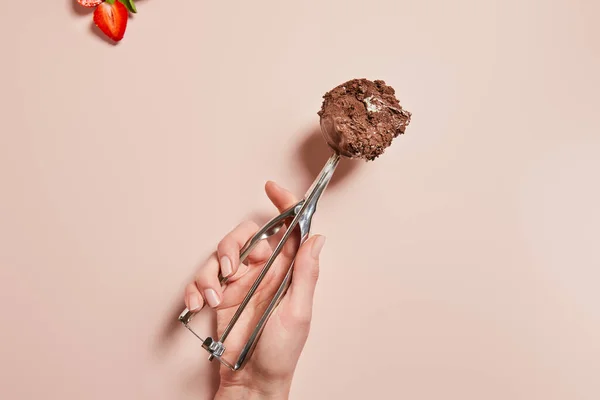 Vue recadrée de la femme tenant une cuillère avec boule de crème glacée au chocolat près de la fraise sur fond rose — Photo de stock