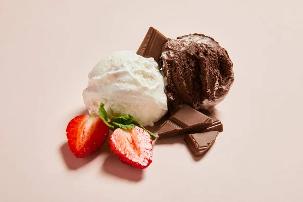 Fresh tasty white and chocolate ice cream balls with mint and strawberry on pink background — Stock Photo