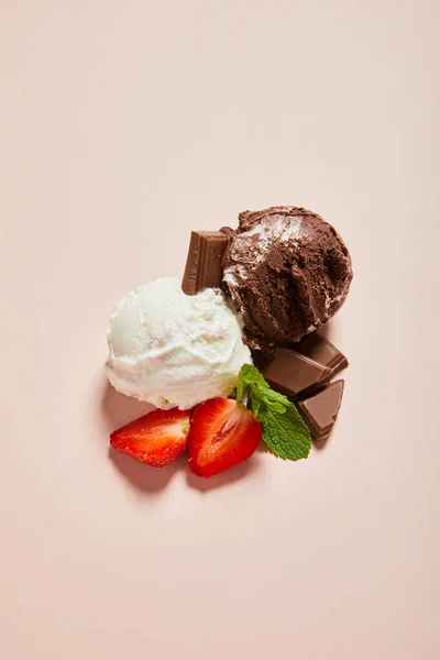 Вид сверху на свежий вкусный белый и шоколадный шарики мороженого с мятой и клубникой на розовом фоне — стоковое фото