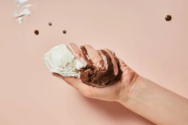 Vue recadrée de la femme tenant crème glacée brune et blanche fondue sur fond rose — Photo de stock