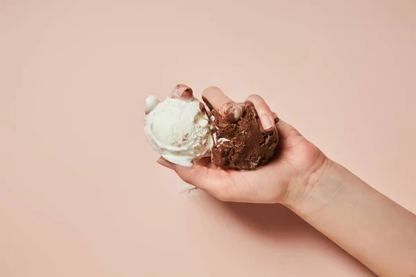 Cropped view of woman holding melted brown and white ice cream on pink background — Stock Photo