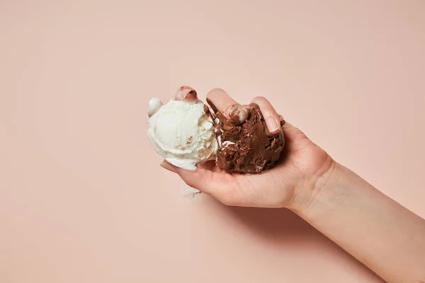 Vista recortada de la mujer sosteniendo helado marrón y blanco derretido sobre fondo rosa - foto de stock