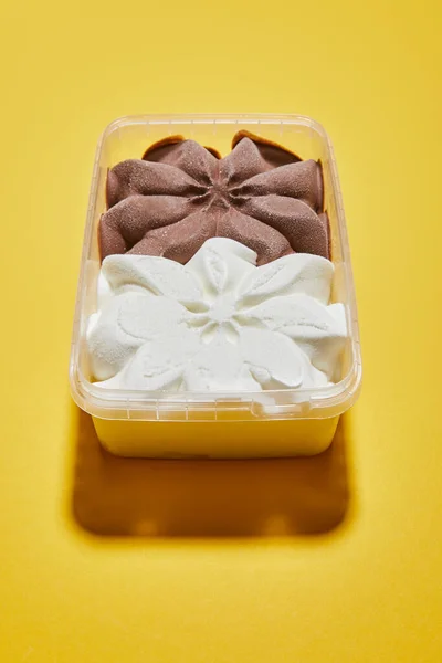 Свіже смачне коричневе та біле морозиво в контейнері на жовтому фоні — стокове фото