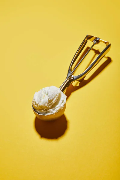 Fresh tasty ice cream ball in scoop on yellow background — Stock Photo