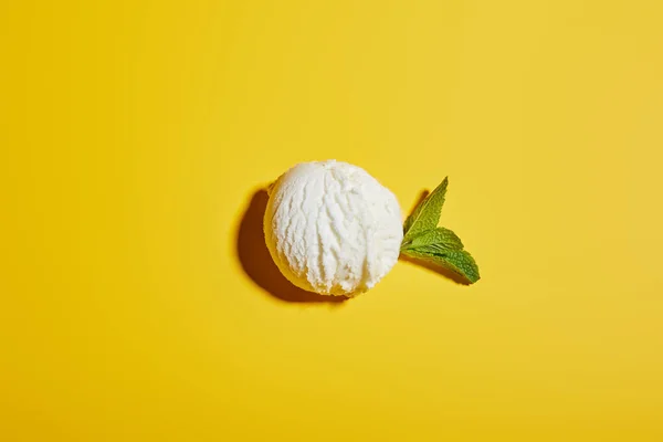 Draufsicht auf frische leckere Eiskugel mit Minzblättern auf gelbem Hintergrund — Stockfoto