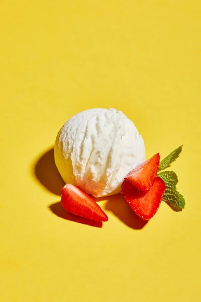 Frische leckere Eiskugel mit Minzblättern und Erdbeere auf gelbem Hintergrund — Stockfoto