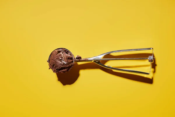 Top view of fresh chocolate ice cream ball in scoop on yellow background — Stock Photo