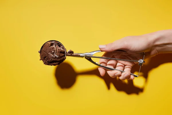 Visão parcial da mulher segurando bola de sorvete de chocolate fresco em colher no fundo amarelo — Fotografia de Stock