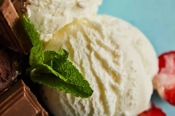 Vista de cerca de sabroso helado blanco con chocolate y menta sobre fondo azul - foto de stock