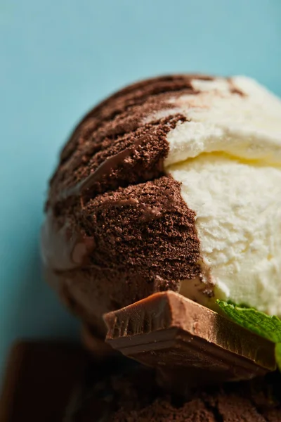 Close up view of tasty brown and white ice cream with chocolate and mint on blue background — Stock Photo