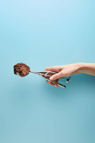 Vista cortada de mulher segurando colher com sorvete de chocolate no fundo azul — Fotografia de Stock