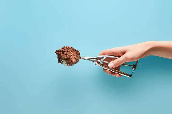 Vista cortada de mulher segurando colher com sorvete de chocolate no fundo azul — Fotografia de Stock