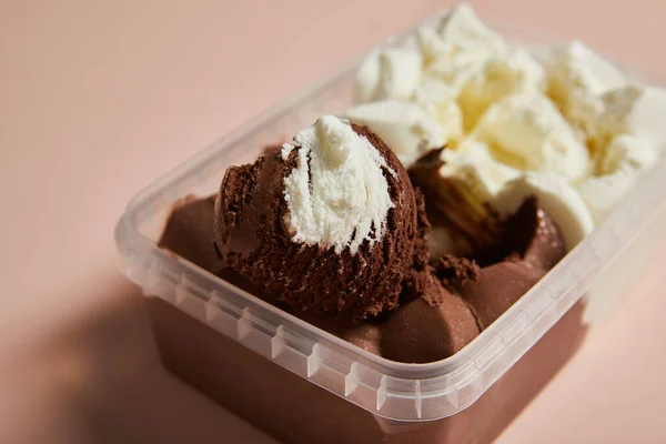 Foyer sélectif de savoureuse crème glacée brune et blanche dans un récipient en plastique sur fond rose — Photo de stock