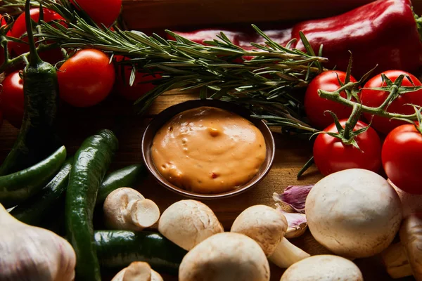 Delicious sauce in bowl near fresh ripe vegetables, rosemary and mushrooms — Stock Photo