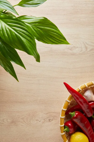 Vue de dessus des feuilles vertes et des légumes frais mûrs dans le panier sur la table en bois — Photo de stock