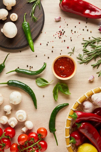 Vista superior de delicioso molho de tomate na tigela perto de legumes maduros frescos, ervas, especiarias e cogumelos na mesa de madeira — Fotografia de Stock