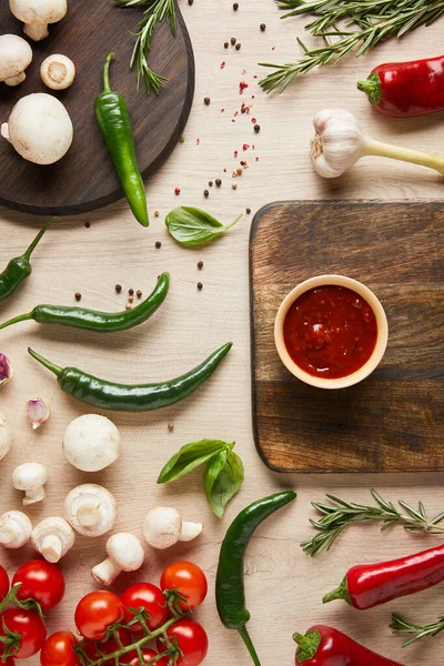 Vue du dessus de délicieuse sauce tomate dans un bol à bord près de légumes frais mûrs, herbes, épices et champignons sur table en bois — Photo de stock