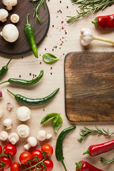 Top view of empty board near fresh ripe vegetables, herbs, spices and mushrooms on wooden table — Stock Photo