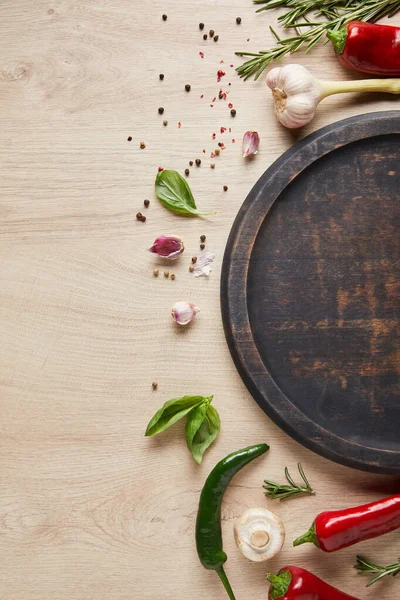 Top view of empty board near fresh herbs, spices and mushroom on wooden table — Stock Photo