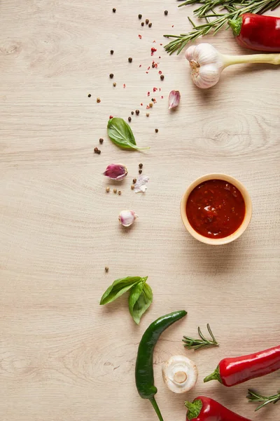 Vue du dessus de la délicieuse sauce tomate dans un bol près des herbes et des épices sur une table en bois — Photo de stock