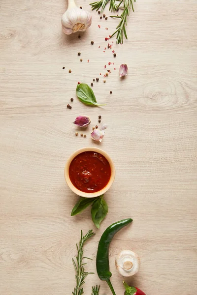 Vista dall'alto di deliziosa salsa di pomodoro in ciotola vicino a erbe e spezie sul tavolo di legno — Foto stock