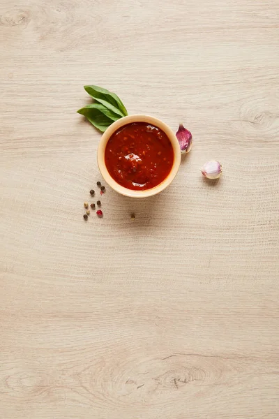 Vista superior de delicioso molho de tomate na tigela perto de especiarias na mesa de madeira — Fotografia de Stock