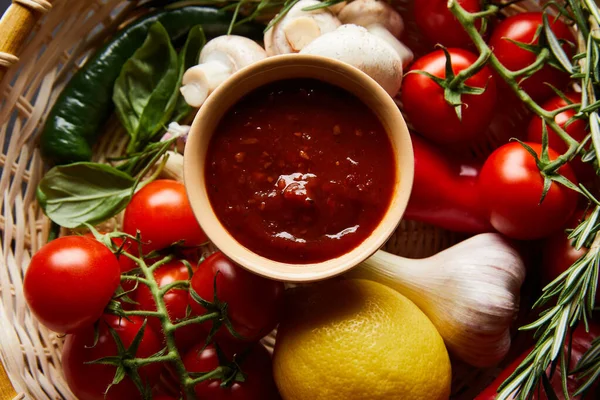 Vista superior de la deliciosa salsa de tomate con verduras frescas maduras en cesta - foto de stock