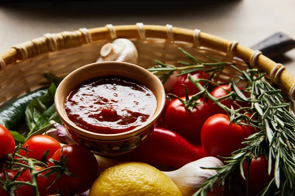 Вкусный томатный соус со свежими зрелыми овощами в корзине — стоковое фото