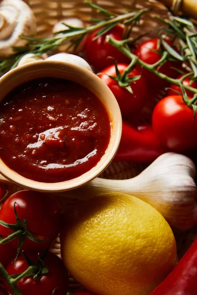 Vista de cerca de la deliciosa salsa de tomate con verduras frescas maduras en la cesta - foto de stock