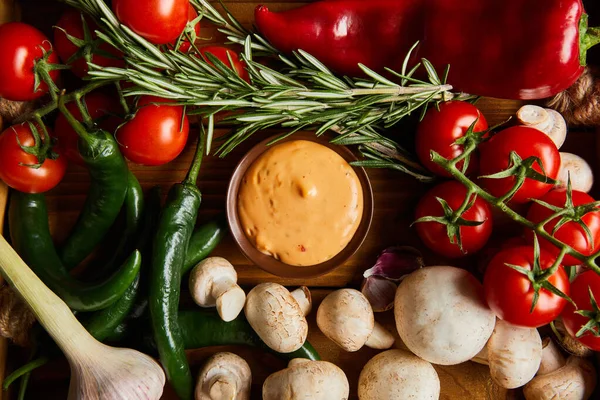 Top view of delicious sauce in bowl near fresh ripe vegetables, rosemary and mushrooms — Stock Photo