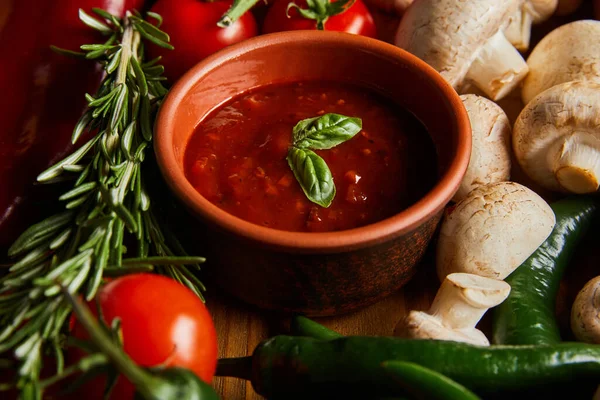 Селективний фокус томатного соусу з листям базиліка біля помідорів вишні, зеленого перцю чилі, грибів та розмарину — стокове фото