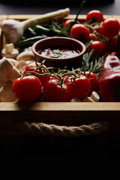 Selective focus of mushrooms, red cherry tomatoes, tomato sauce near rosemary and chili peppers in wooden box — Stock Photo