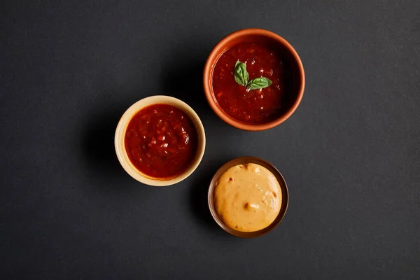Top view of bowls with tomato and mustard sauces on black — Stock Photo
